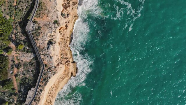 Top-down view of the wooden boardwalk and ocean waves. Carvoeiro, Portugal