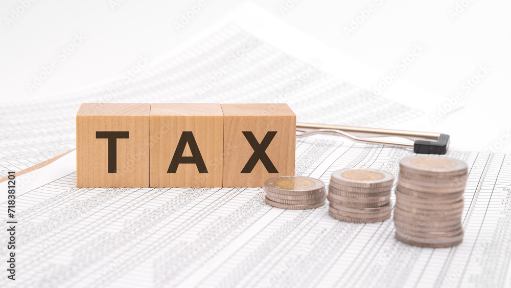 Poster tax text is written in wooden cubes on a table with numbers with coins on a white background