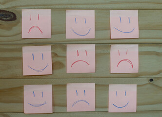 Drawing of several sad faces surrounded by happy faces drawn on post it