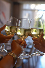 Hands with glasses of white wine, close-up, restaurant, party, meeting friends