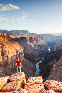 Man standing on the edge of the Grand Canyon at sunset, Arizona, United States