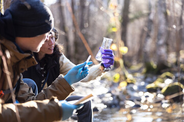 Adult Female Biologist Asking Her Younger Assistant to Explain What he See in the Taken Water...