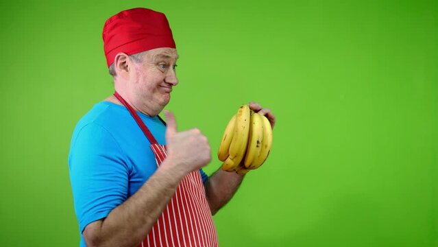 Senior cook in apron pointing finger stem bananas.