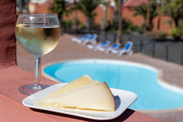 Spanish hard manchego, cow, sheep and goat cheese, cold white wine and blue swimming pool on...