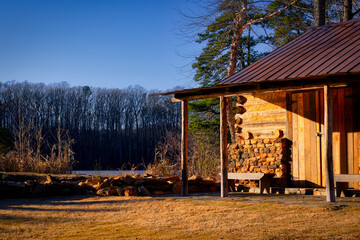 A landscape at sunset of an old cabin by a lake in the woods at Yates Mill Park in North Carolina.