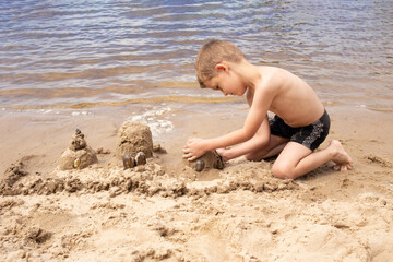 closeup portrait of a happy boy on the beach during summer vacation. On weekends, children build a sand castle by the sea