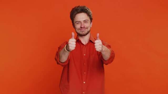 Like. Caucasian man raises thumbs up agrees with something or gives positive reply recommends advertisement likes good idea feedback celebrating success victory. Guy isolated on orange background