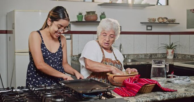 Latin girl and her grandmother make corn flour tortillas in their home.