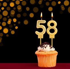 Number 58 birthday candle - Cupcake on black background with out of focus lights