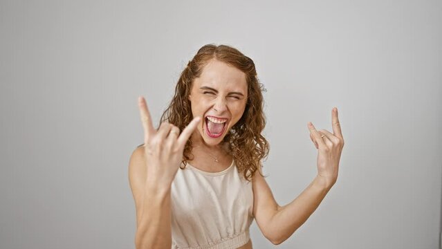 Frenzied young woman, an emerging star in the heavy music scene, standing with a crazy rock 'n roll expression. gesturing rock symbol with hands, isolated on a white background.