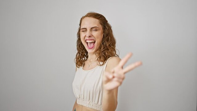 Young woman standing smiling looking to the camera showing fingers doing victory sign. number two. over isolated white background