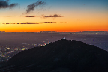 sunrise, sunset over hillside, mountain silhouetted agains city, town