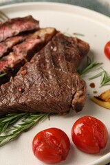 Delicious grilled beef steak, tomatoes and rosemary on plate, closeup
