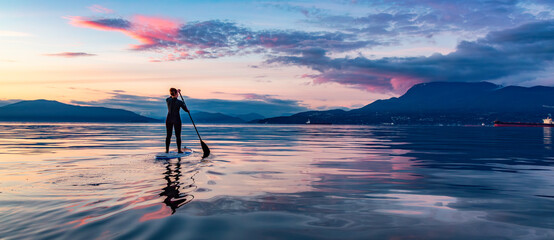 Adventurous girl on a paddle board. Sunset Sky Nature Panorama.