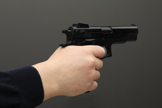 Man with handgun on dark gray background, closeup