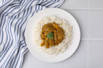 Delicious chicken curry with rice on white tiled table, top view