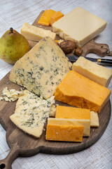 English cheeses collection, mature and coloured cheddar cheese and semi-soft, crumbly old stilton blue cheese close up