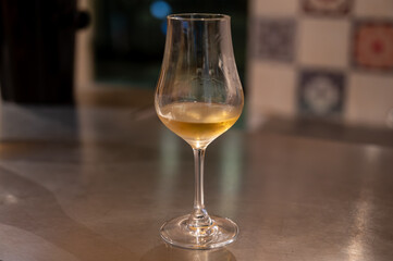 Tasting of cognac spirit aged in old French oak barrels in cellar in distillery in Cognac white...