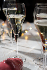 New year party, small bubbles of brut champagne cava or prosecco wine in tulip glasses with garland  lights on background