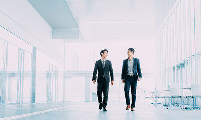 オフィスを歩く2人の男性ビジネスマン - obrazy, fototapety, plakaty