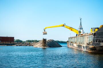 urban enviromental remediation: gravel is unloaded from a large barge directly into toronto s inner harbour as part of a project to create an artificial marsh at the moth of the don river