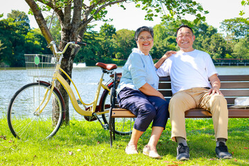 Elderly Asian couple sitting in a park Smiling happily with retirement life. Elderly health insurance. financial stability