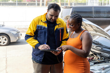 Mechanic holding a clipboard and showing the car checking list and repaired item to woman customer...