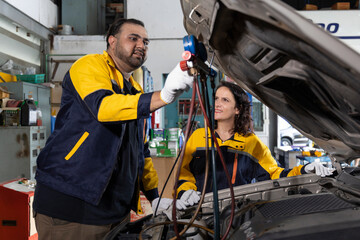 Professional Uniformed Car Mechanic Working in Service Station. Repairing Vehicle. Checking Air Conditioner. Car's Engine in The Uniform Works in Checking Air Conditioner. Selective Focus