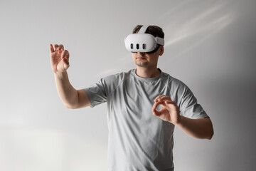 A man is using a VR  AR headset against a gray background. Strong emotions and impressions from using the VR AR headset.