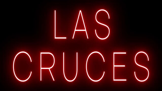 Flickering red retro style neon sign glowing against a black background for LAS CRUCES