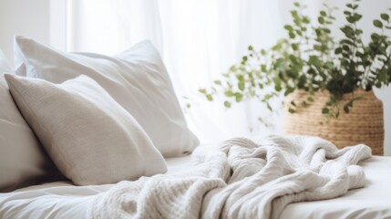 Bright and airy bedroom design with white bedding, a knitted throw, and fresh green plants.
