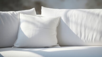 Fototapeta na wymiar Sunlit living room scene highlighting white pillows on a contemporary sofa with soft shadows.