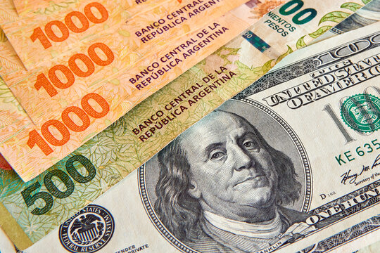 Close-Up Wealth: Detailed View of US $100 Bill and Argentine Peso Bills, Symbolizing Economic Perspectives