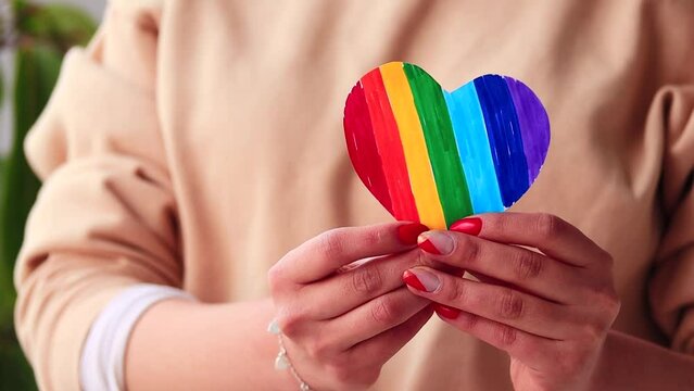 Video of woman's hands holding a hand drawn LGBTQ+ heart. Concept of people and lifestyles.