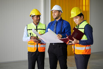 workers and architect holding plan blueprint paper and looking to something at construction site
