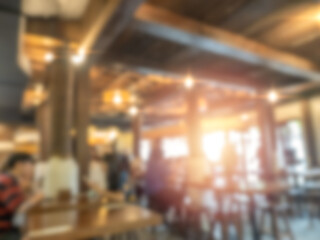 Fototapeta na wymiar Abstract blurred restaurant wooden building background, warm light indoor interior cafe or club with window and sun light from outside. Blurry backgrounds for advertising and business presentation.
