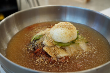Naengmyeon is one of Korea's unique cold noodle dishes, made by putting boiled noodles in cold broth and topping them with seasoning and toppings.