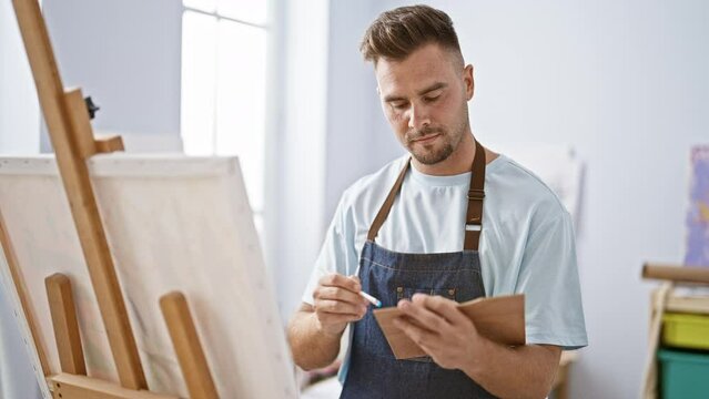 A focused man painting on canvas in a bright art studio, embodying creativity and concentration.