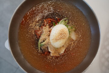 Naengmyeon is one of Korea's unique cold noodle dishes, made by putting boiled noodles in cold broth and topping them with seasoning and toppings.