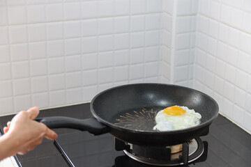 asian women cooking indoor kitchen with fried egg in the pan 