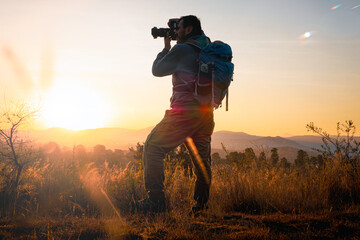  With camera and backpack, the photographer ventures at dawn among the mountains. adventurer concept, local travel, photography