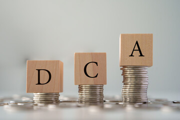 DCA text on wooden blocks on growth of coins stack. Background for Dollar cost averaging investment strategy, Saving stock monthly, Quarterly basis. Fund purchases, Business and investment concept.