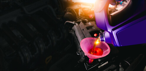 Engine oil poured into a funnel in the engine oil filler on a black background with copy space , Car maintenance service concept