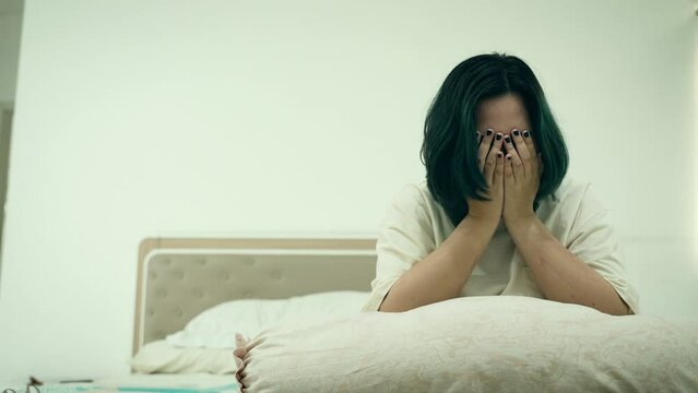 Depressed Asian woman covering her face crying