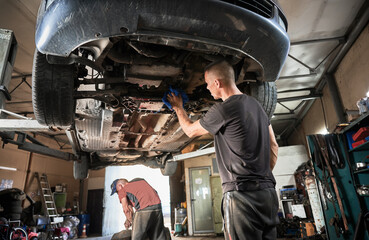 Back view of men working in auto station, servicing center. Mechanics, workers, repairmen servicing...