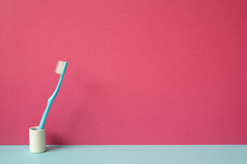 Toothbrush in holder on skyblue shelf. pink wall background