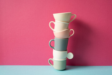 Stack of colorful coffee cups on skyblue table. pink wall background
