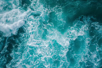 From above aerial view of turquoise ocean water with splashes and foam for abstract natural background and texture.