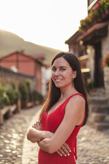 Portrait of young hispanic woman standing with crossed arms. She is in a rural town during sunset.