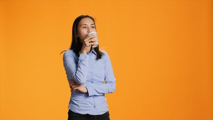 Filipino person savouring cup of coffee in studio, drinking caffeine refreshment for energy through...